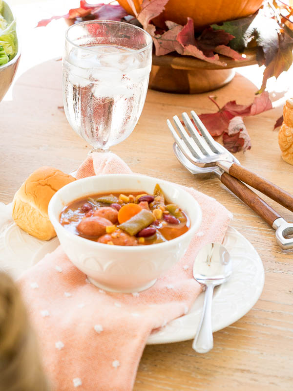 Bowl of homemade vegetable soup in a white bowl with bread and water.