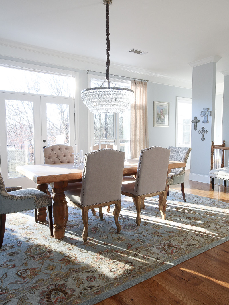 room shot of dining room , wood table and hanging crystal chandelier