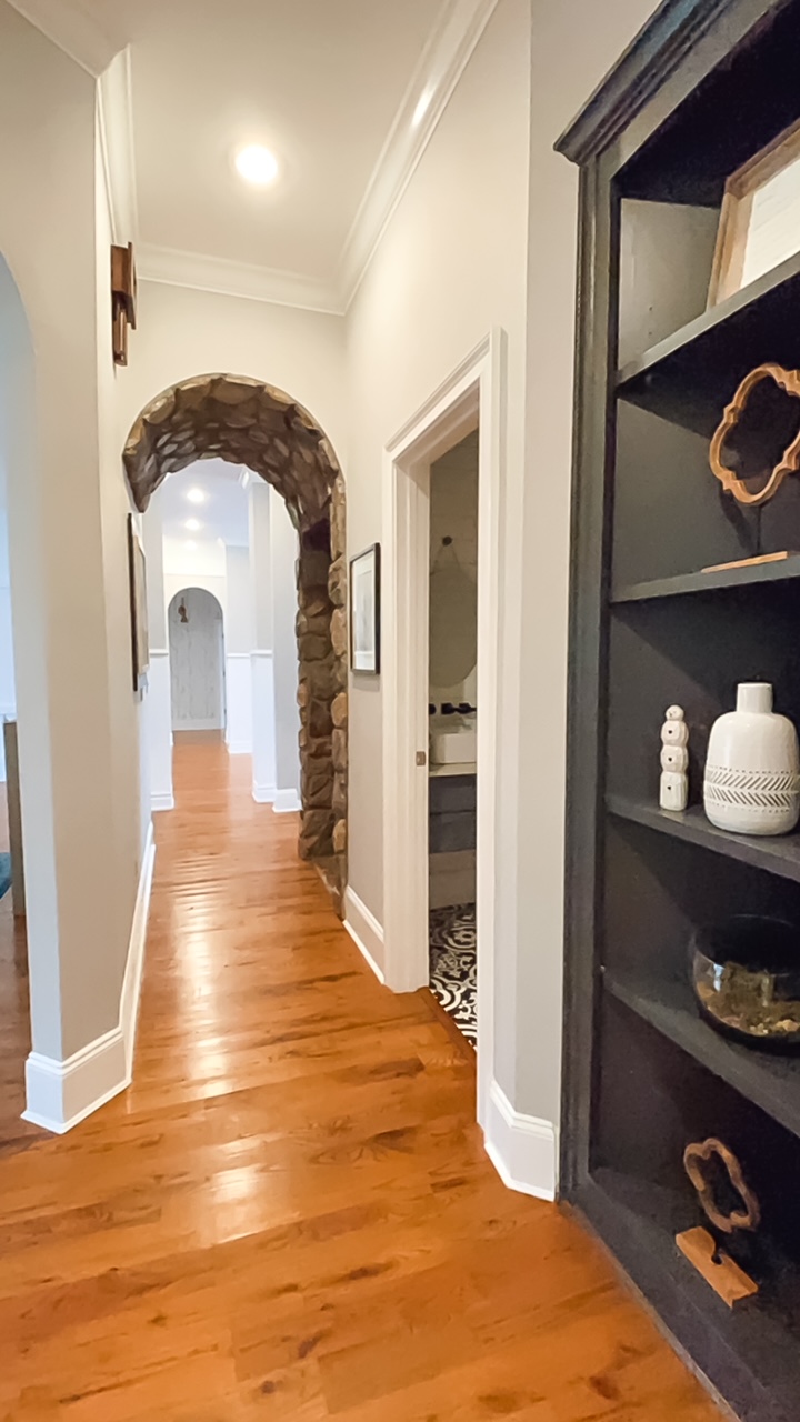 Hallway with stone arch and bookcase.
