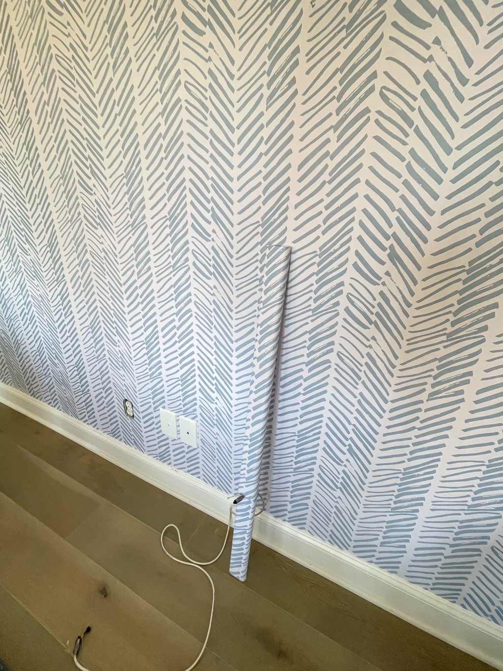 blue and white wallpapered wall with covered cord cover