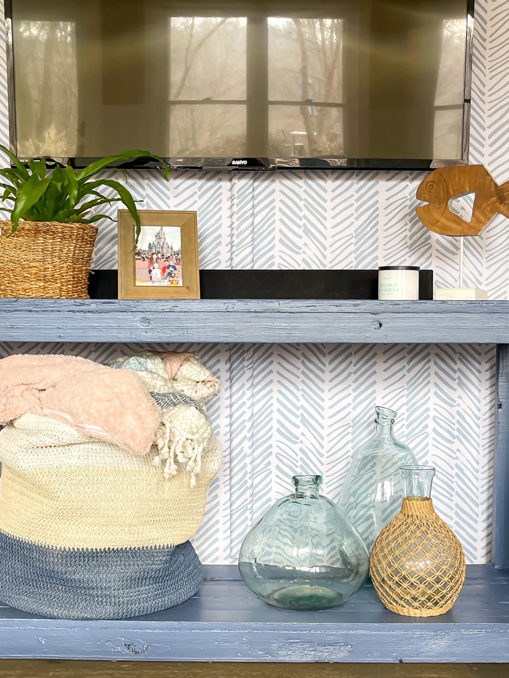 styled console table in blue against blue and white wallpapered wall