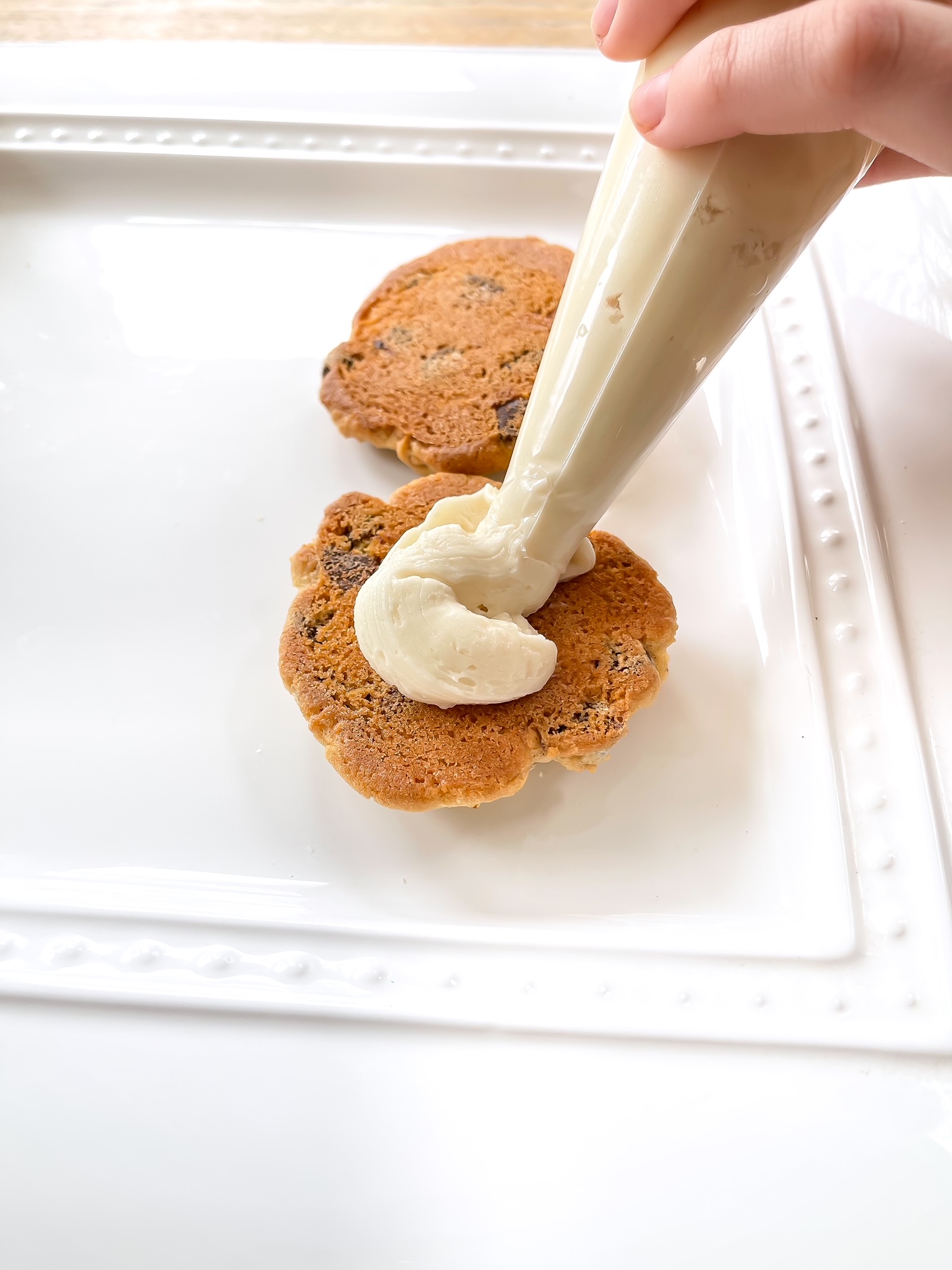 applying white frosting to a cookie