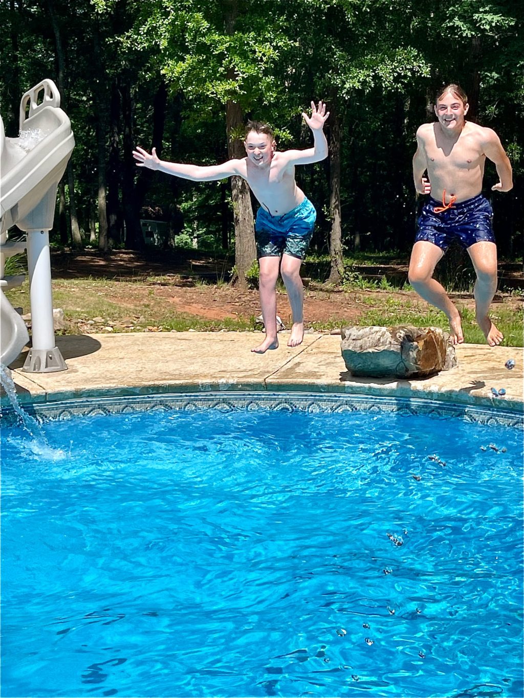 two boys jumping in a pool
