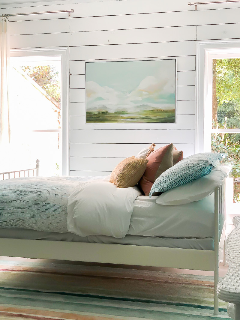 Beach inspired bedroom with white wood planked walls and white bedding.