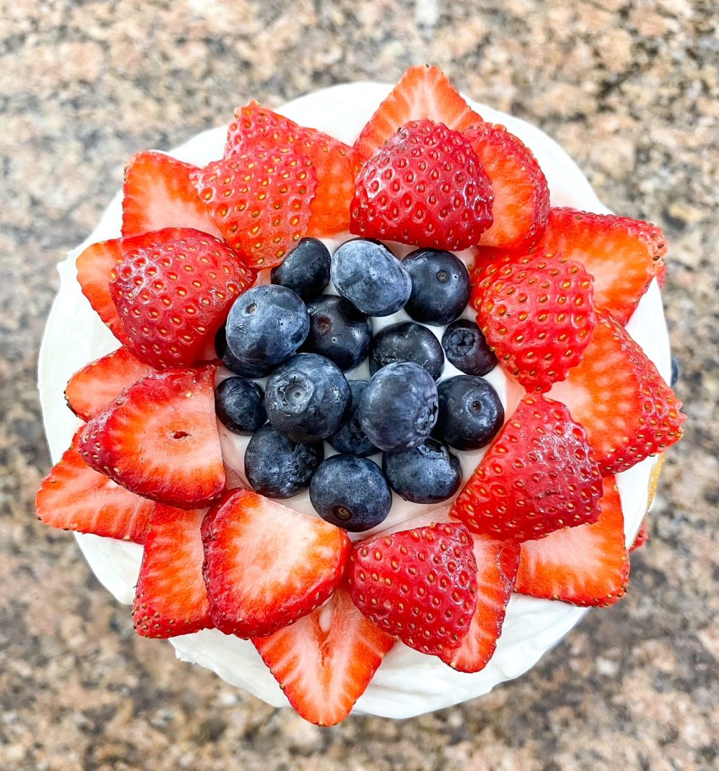 strawberry flower with blueberries in the middle on top of a layered cake