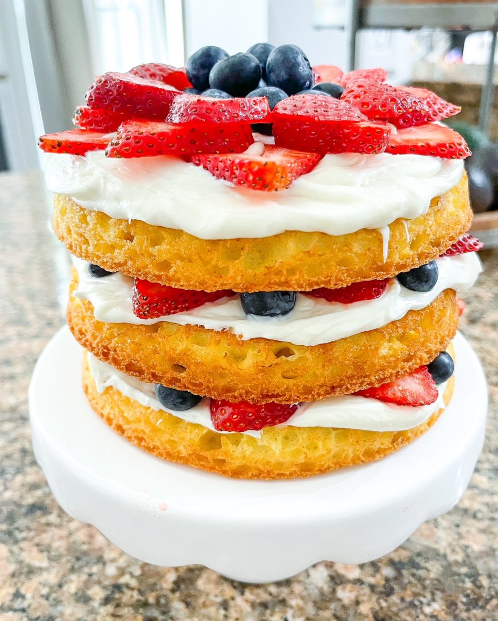 full shot of three layers of cake with frosting and fruit in the middle