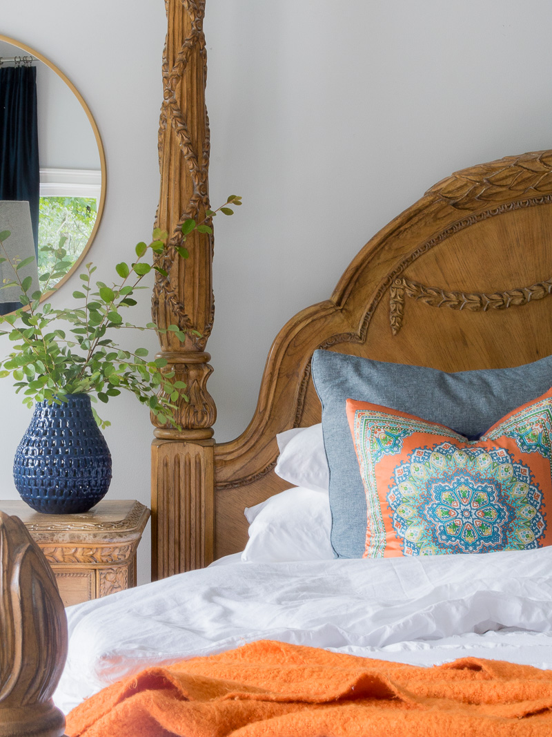 Bed with white comforter and blue and orange accents.