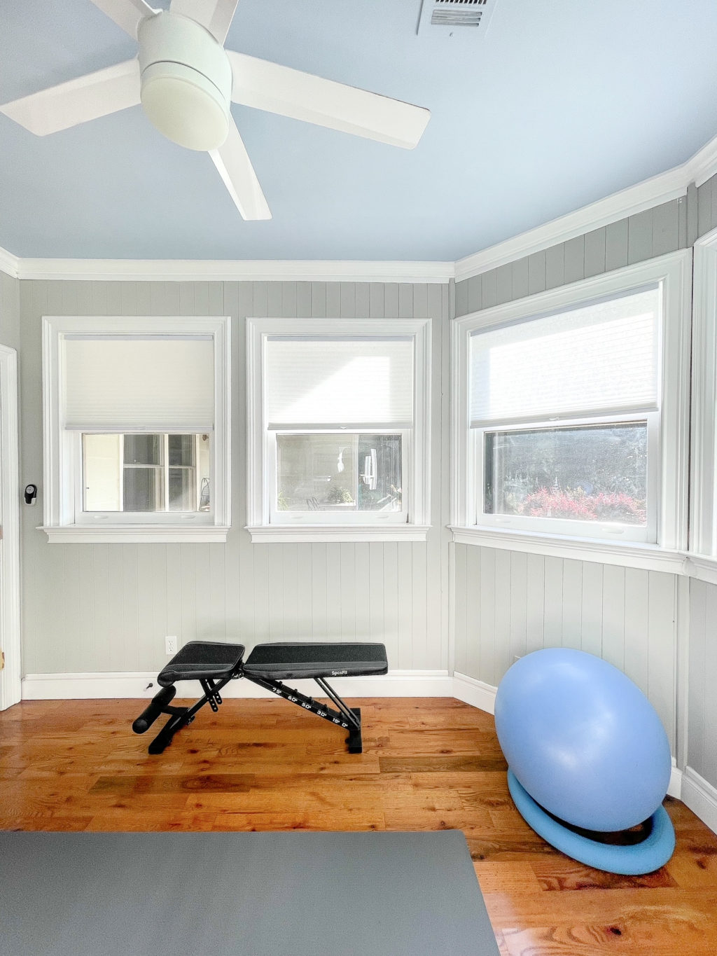 Small home gym with a weight bench and blue exercise ball.