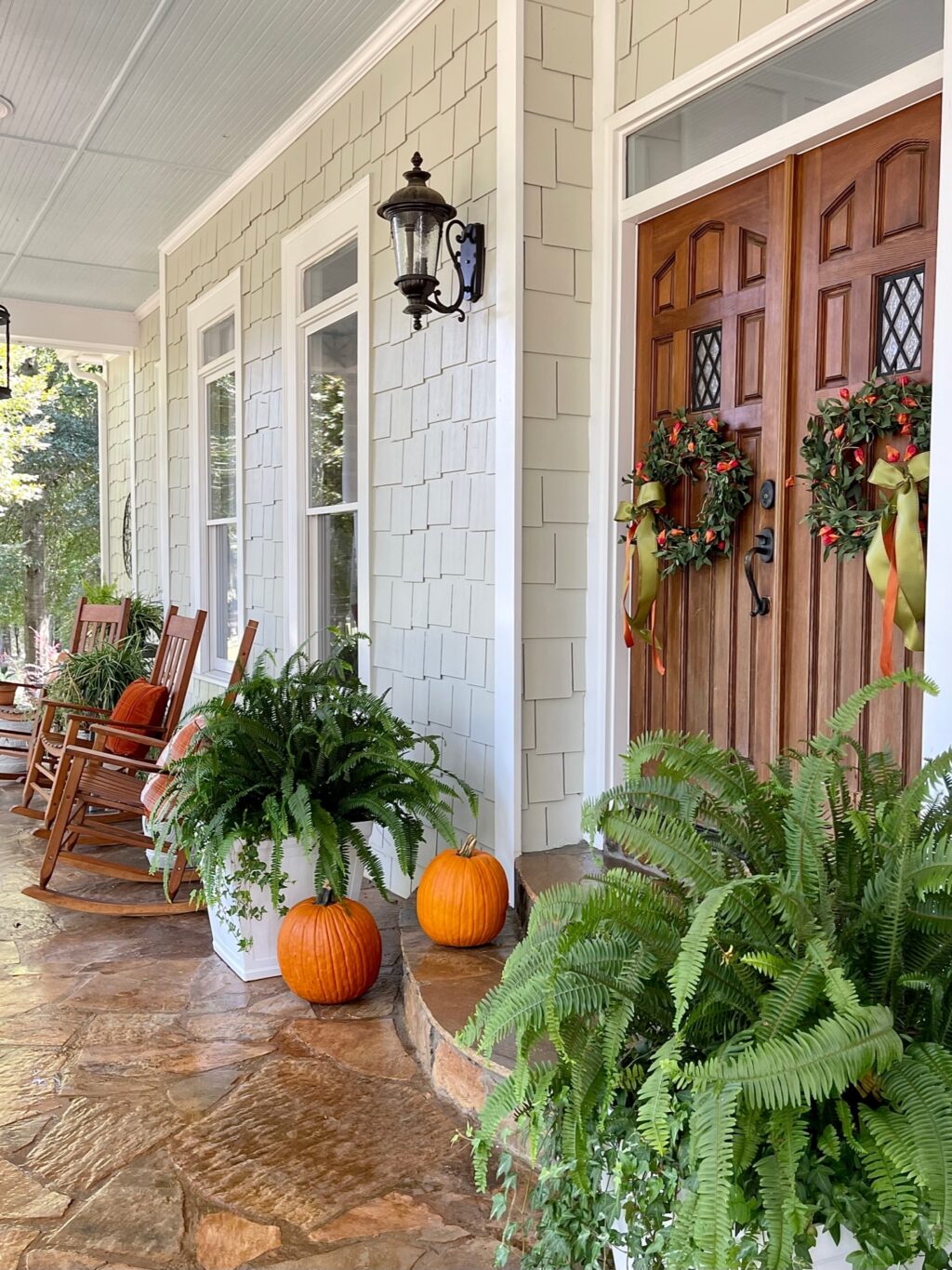 Front porch with double wood doors with fall wreaths hanging.