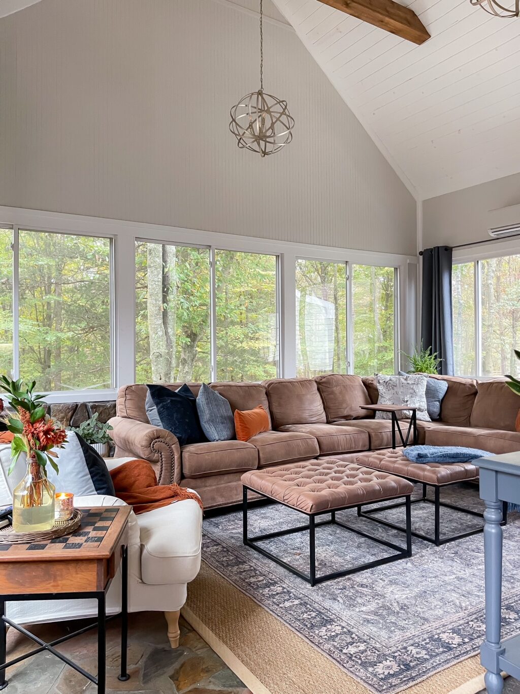Family room with brown sectional and white accent chair with blue and rust colors.