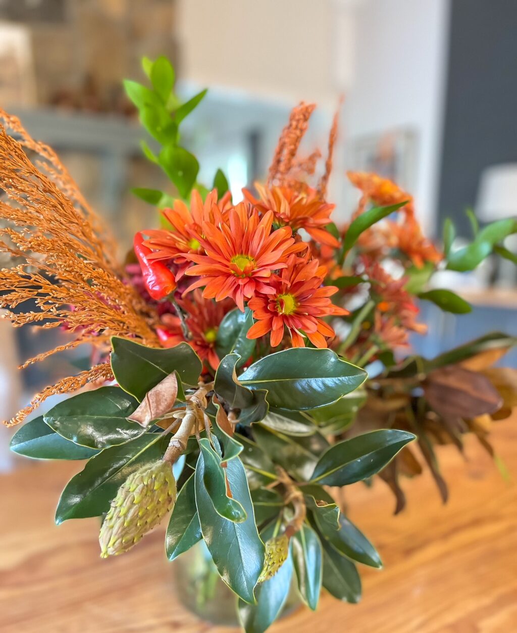 over head of flower arrangement with magnolia leaves and dried fall floral stems.