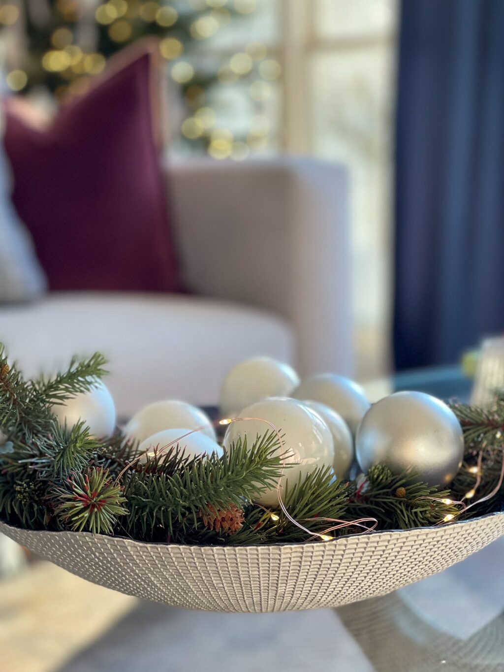 Bowl filled with evergreen and white and silver balls and fairy lights