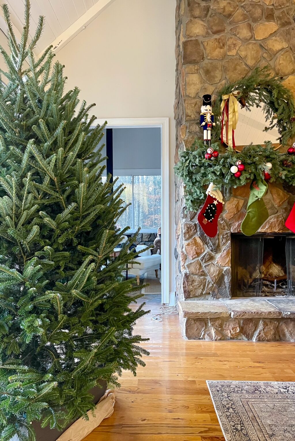 Undecorated christmas tree in room with fireplace in the background.