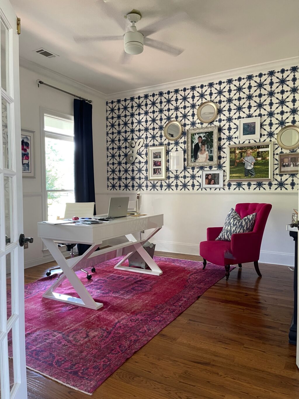 White office walls with blue patterned wallpaper and pink chair.