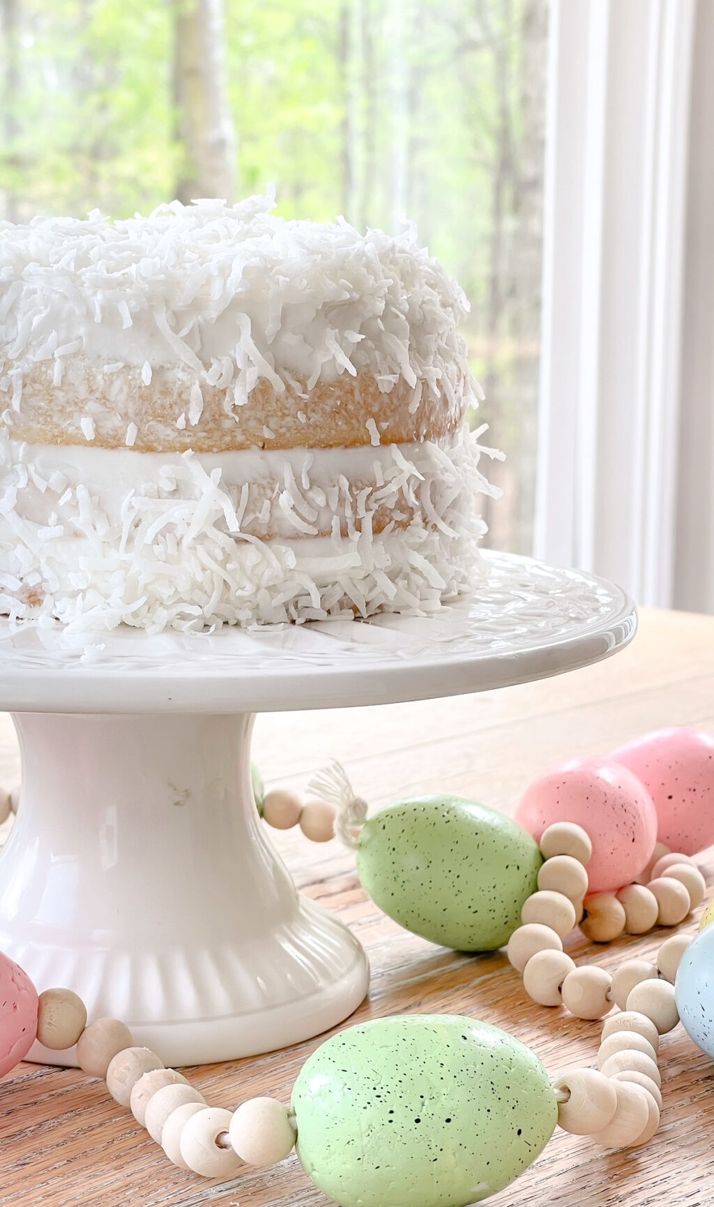 white layered cake with coconut on a white cake plate