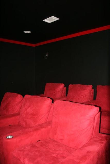 home media room with black walls and red chairs