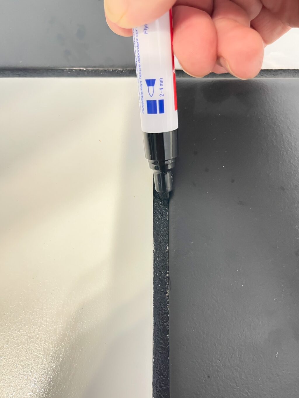 applying grout paint with a grout pen to black grout line