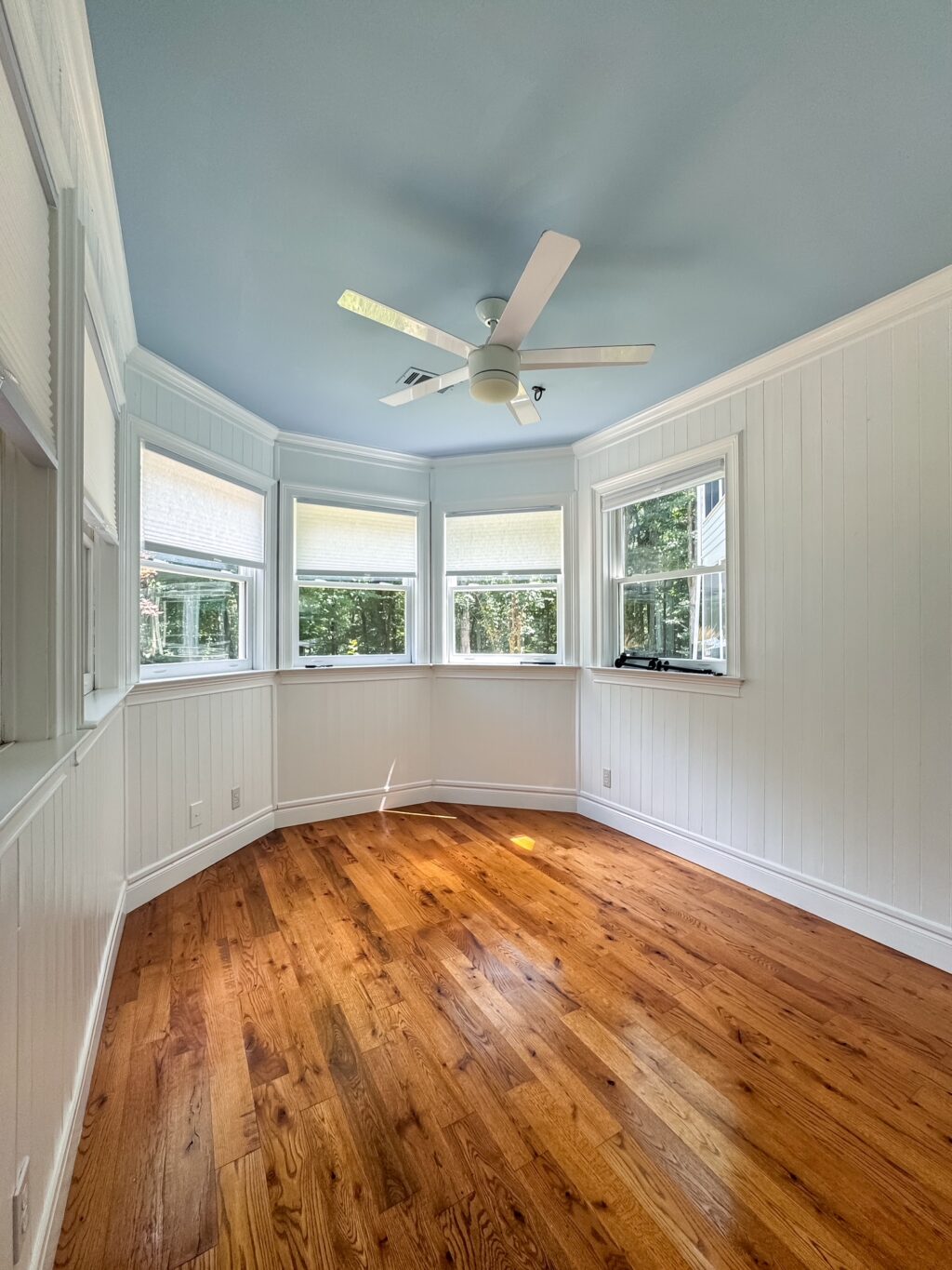 finished space with white walls, light blue ceiling and hardwood floors