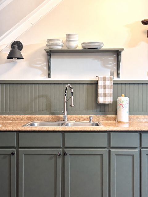 Updated guest house kitchen with sage cabinets and open shelving